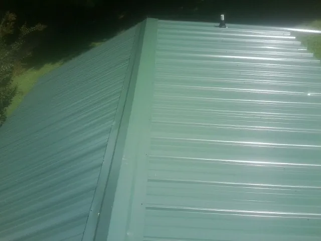New green metal panels meeting at the ridge of a roof — Flat Roof Repair work by our crew in Gillsville