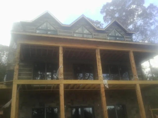 Dormers and porch framing on a large log home under construction — Roof Coating work by our crew in Gillsville