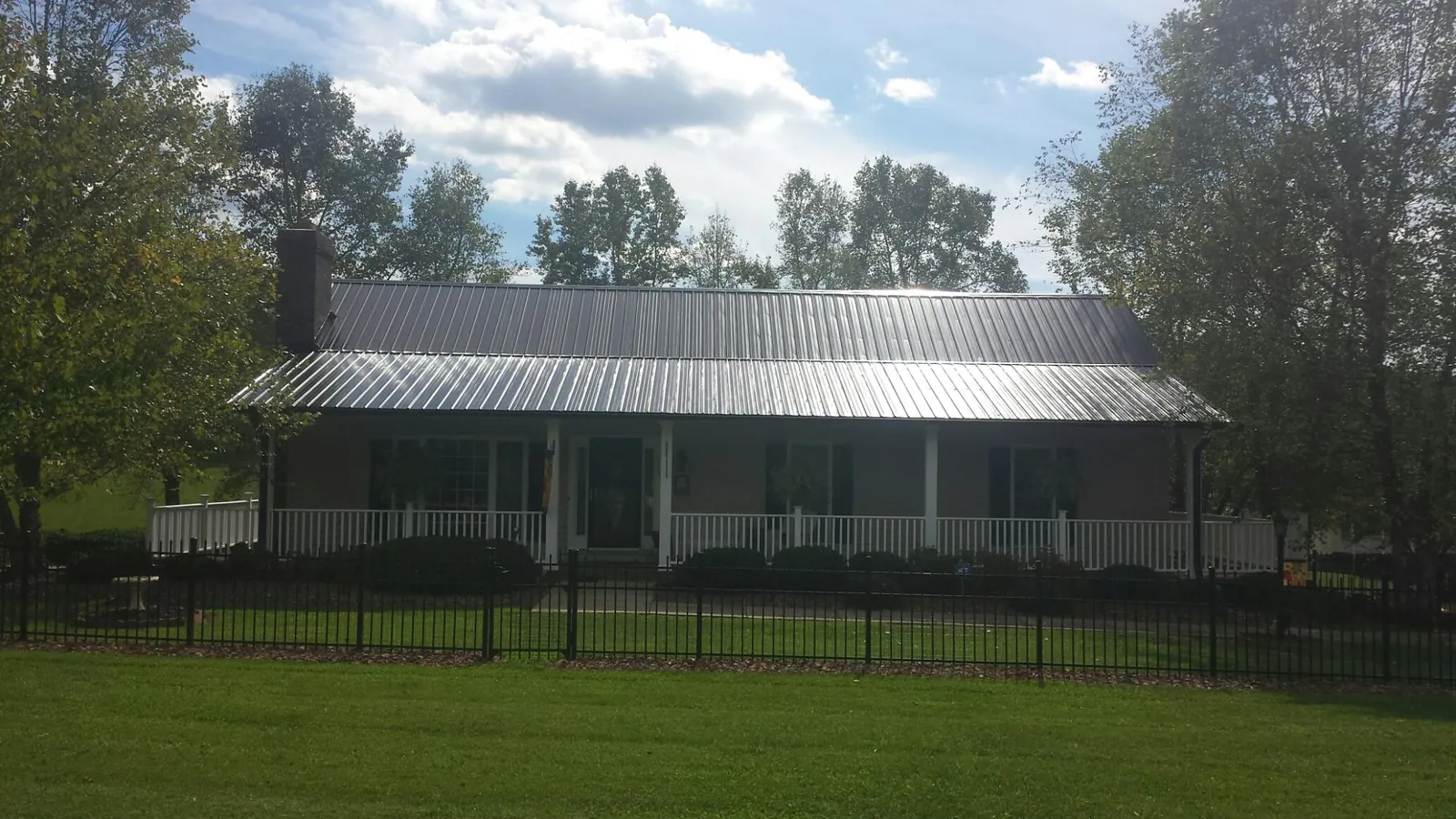 Gray metal roof on a brick ranch with a full width front porch — Gutter Guard Installation work by our crew in Gillsville
