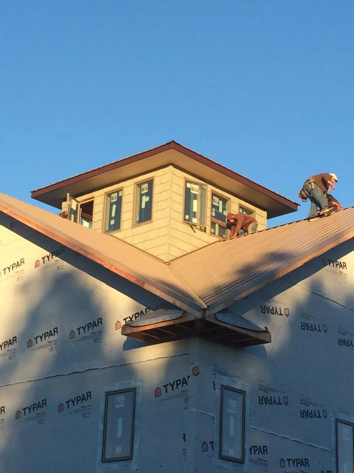 Roofers working around a rooftop cupola on a new metal roof at sunset — Roof Waterproofing in Gillsville by Roofing Brothers